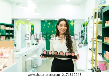 Beautiful young woman making a product demonstration while working as a salesperson at the make up shop Royalty-Free Stock Photo #2171812243