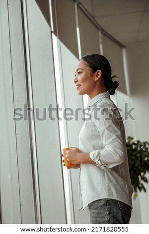 Charming asian business woman drinking coffee standing near windows at office. High quality photo