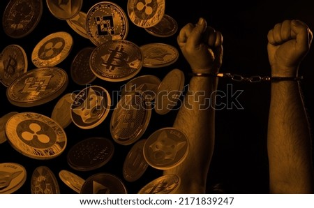 Hands in handcuffs and cryptocurrencies over dark background. Crypto crime concept. 