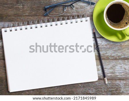 Top view blank notebook,glasses and coffee on wood table background on office desk. Business and Marketing concept.