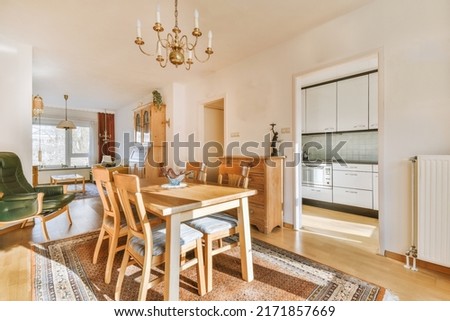 Table with chairs and a vase next to the living room and kitchen in a spacious room of a modern apartment