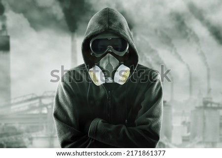 Hooded man wearing gas mask while standing with confident expression in the polluted city Royalty-Free Stock Photo #2171861377