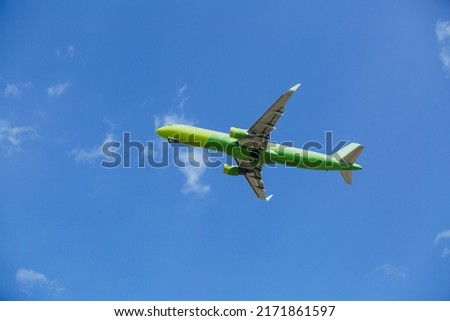 Passenger plane of yellow-green color flies in the blue sky with white clouds,, air transportation concept, population evacuation.