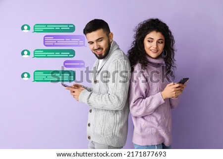 Happy young couple with mobile phones chatting online on lilac background