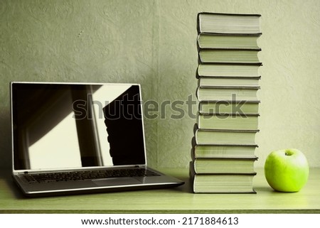 Office desk with laptop blank screen, green apple and stack of books. student workspace with laptop computer empty screen mockup on wooden table
