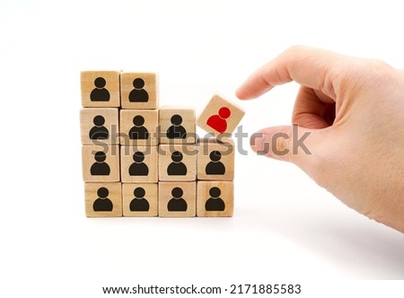 hand pick a wooden cube block with red people icon out of black icon represent concept of talent , leadership , outstanding and right candidate in the business or organization 