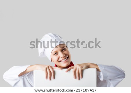 Female chef holding a poster for text, look at the poster and smiling on a white background