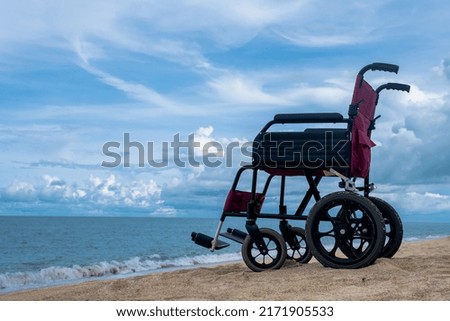 Empty disabled wheelchair parking on sand beach with ocean waves and blue sky in summer, disability wheelchair on beach, physically challanged wheelchair, differently abled traveller concept  Royalty-Free Stock Photo #2171905533