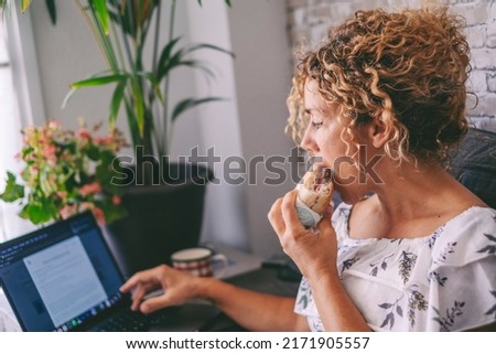 One woman working on laptop and eating a sandwich for lunch break time. Modern people work on computer at home. Alternative office and digital online job concept. Fast food nutrition concept lifestyle Royalty-Free Stock Photo #2171905557