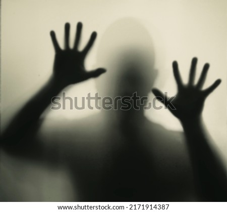 Horror, halloween background - Shadowy figure behind glass of a man
