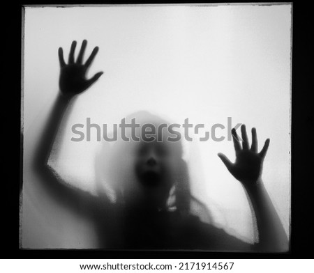 Horror ghost girl behind the matte glass in black and white. Halloween festival concept.