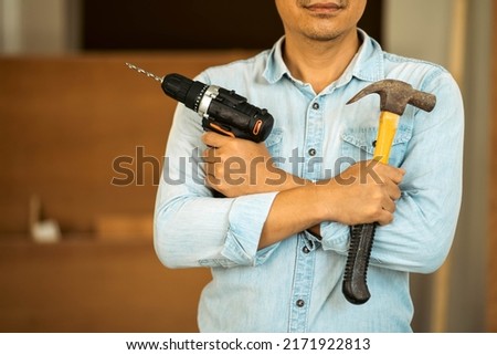 Choseup of carpenters working with electric drill and hammer in a carpentry workshop.