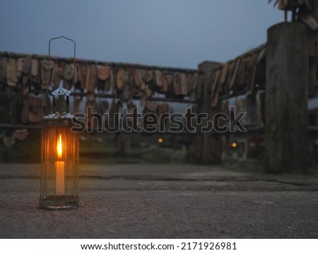 Vintage lamp with candle inside on street over wood name plates and tied to the bridge rail background in evening at E-tong village, Pilok mine, Kanchanaburi in Thailand.