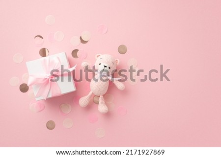 Baby concept. Top view photo of white giftbox with ribbon bow knitted teddy-bear toy and shiny confetti on isolated pastel pink background Royalty-Free Stock Photo #2171927869