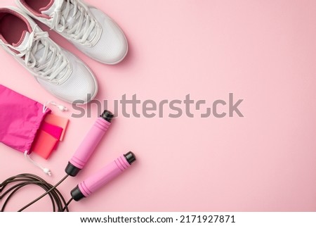 Fitness accessories concept. Top view photo of white sneakers pink resistance bands in special bag and skipping rope on isolated pastel pink background with copyspace