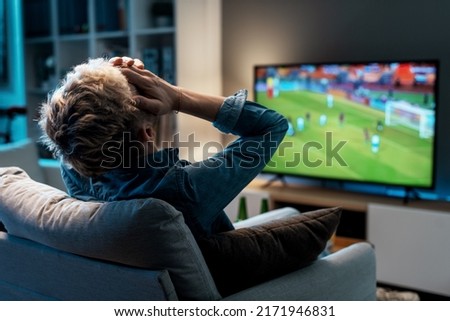 Disappointed man watching his football team losing the match on TV Royalty-Free Stock Photo #2171946831