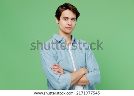Tired fatigued displeased unnerved tired gloomy young brunet man 20s years old wears blue shirt hold hands crossed isolated on plain green background studio portrait. People emotions lifestyle concept Royalty-Free Stock Photo #2171977545