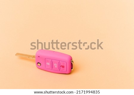 Pink car keys isolated on beige background