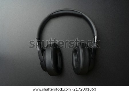 Headphones on a black background. Stylish studio headphones for listening to music, sounds, radio and podcasts lie on an empty dark table.