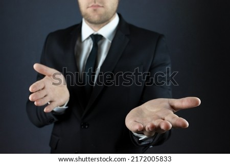 A businessman in a suit spreads his hands palms up. Gesture of not understanding, helplessness, presentation.
