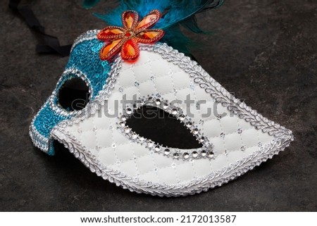 white and blue masquerade mask on mottled surface with copy space