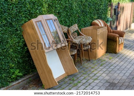 Items and old furniture on street outside house moving day or getting rid of junk and household storage concept. Old damaged furniture extruded on a pile of unnecessary things on the pavement. Royalty-Free Stock Photo #2172014753