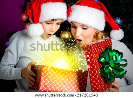 Mother with little child opens the box with gifts on the christmas holiday - indoors