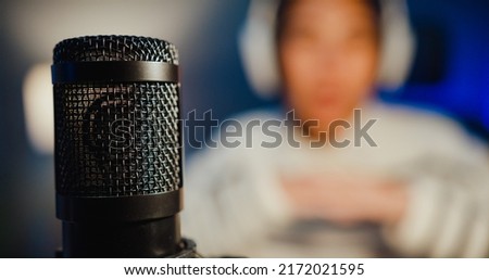 Happy asia lady blogger music influencer record a podcast on computer with headphones and microphone talk with audience in living room home studio at night. Stay at house, Content creator concept.