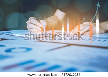 strategic planning stock market management business growth A businessman is writing a virtual display of his growing stock hologram on a notebook. Investing in online market assets