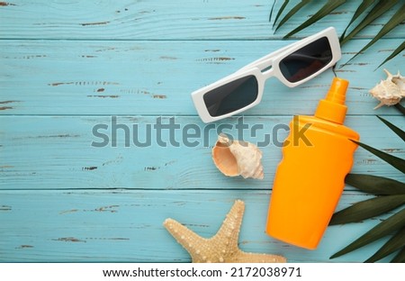 Beach flat lay accessories. Sun hat, palm branch, sunscreen bottle and seashells on blue background. Summer travel holiday concept. Top view