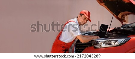 Young man car mechanic electrician is using an laptop computer to check diagnostic the car errors and problems and fix it. 
 Royalty-Free Stock Photo #2172043289