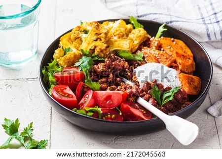 Baked vegetables buddha bowl. Cooked sweet potato, cauliflower, tomato and bean salad. Vegan recipe.