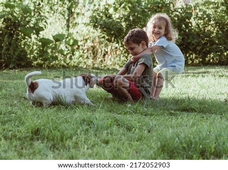 Happy smiling children playing tug-of-war game with their stubborn pet dog