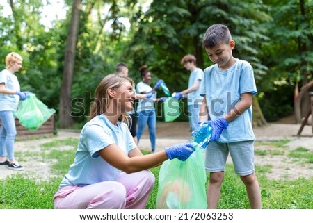 Mother and kids are picking up the garbage to clean up the forest Royalty-Free Stock Photo #2172063253