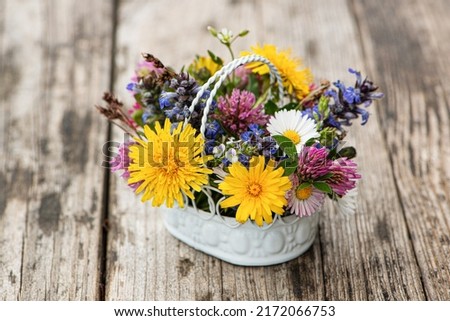 Little wild flower bouquet in a little basket on wooden table Royalty-Free Stock Photo #2172066753
