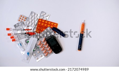 Pile of medicines on white background. Tablets and capsules that doctors prescribe to patients. Insulin syringes, catheters for administration of liquid drugs.Glucometer and syringe pen filled insulin Royalty-Free Stock Photo #2172074989