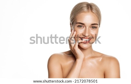 Blond girl with clear, natural skin, moisturized face, smiles with white perfect teeth, stands over white background Royalty-Free Stock Photo #2172078501