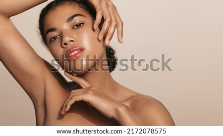 Beautiful african american woman, 25 years old, has glowing skin, nourished face after cream, skincare gel or moisturizer, posing against brown background Royalty-Free Stock Photo #2172078575