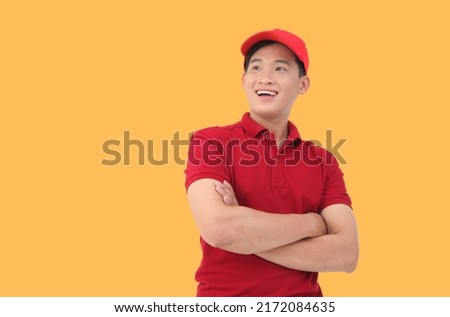 Happy Asian deliveryman smiling and holding package parcel box isolated on yellow background, Delivery courier and shipping service concept.