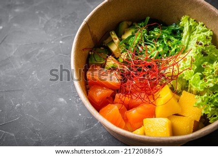 delicious poke bowl with fresh vegetables and seafood on a black background.