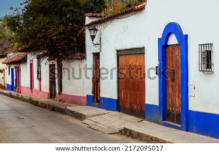 An empty street, exterior view of traditional colorful Mexican buildings in the old town of San Cristobal de las Casas, Chiapas, Mexico. Facades of historical colonial houses on tiny downtown streets. Royalty-Free Stock Photo #2172095017