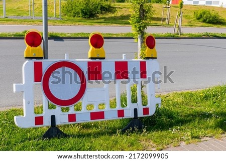 White red plastic barrier with stop signal. Against the background of the road.