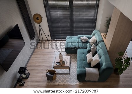 Top view on small and stylish living room with big window with black blinds, cozy sofa, tv, coffee table and decorations Royalty-Free Stock Photo #2172099987