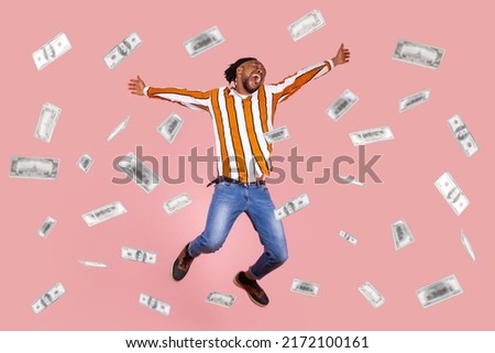 Money rain, winner and rich. Hurray. full length raised arms happy young man jumping with excited amazed face, pleased, amazed with money falling. Indoor studio shot isolated on pink background
