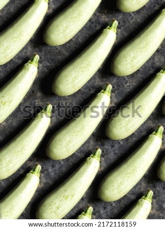 A pattern of young, tender zucchini on a black concrete background. Background of fresh summer vegetables.