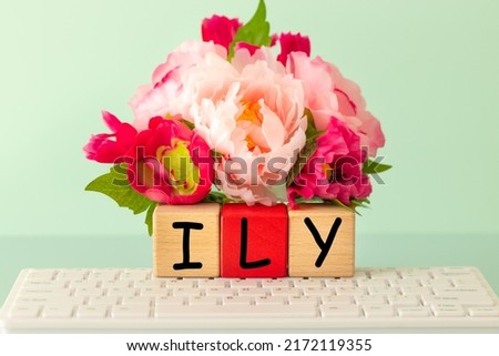 ILY, I love you, Confession of Love, abbreviation used on the web, in correspondence between lovers. The inscription on wooden blocks against the background of a computer keyboard and a bouquet 