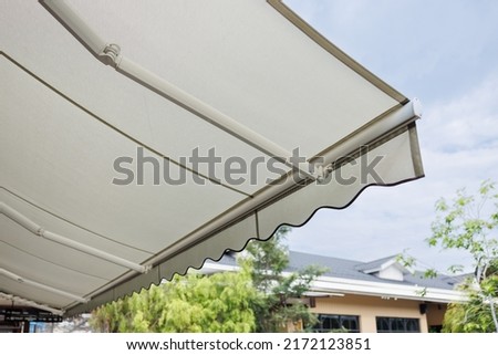 white fabric awning with the garden background. white canvas sun