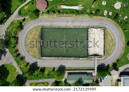 Aerial top down view of an outdoor sports center with football field and circular track for inline racing or skating, located in a local city park