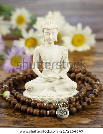 Buddha statue, prayer beads and flowers on a wooden background. Asian spa ritual procedure and meditation. Energetic health and relax. Mental healing. Vesak, Buddha Day. Soft style image Royalty-Free Stock Photo #2172154649