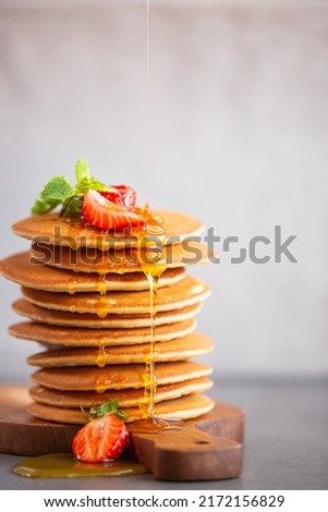 Pancakes for breakfast. Cover with pancakes. A stack of pancakes on a wooden board with honey. Honey pours on pancakes. Dessert. Favorite breakfast. Beautiful food cover.American breakfast.  Royalty-Free Stock Photo #2172156829